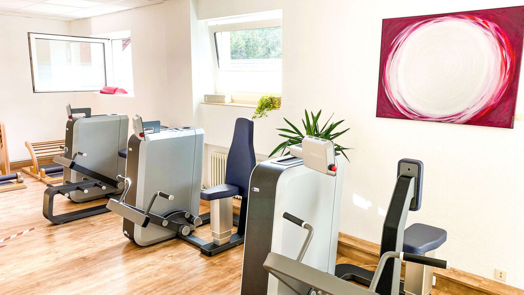 Heller Raum mit mehreren Therapie- und Trainingsgeräten